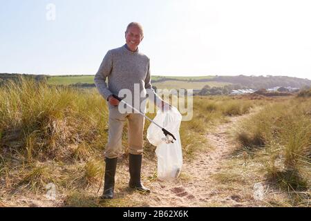 Portrait Des Älteren Mannes, Der Wurf Am Winter Beach Sammelt, Säubern Sie Sich Stockfoto