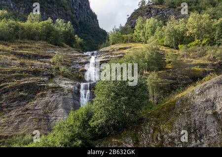 Wasserfall fällt, norwegischer Fjord Aurlandsfjord Reise. Helle Aussicht auf die wilden grünen Berge in der Natur Norwegens. Sonniger Tag in Skandinavien. Stockfoto