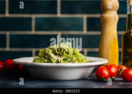 Italienische Nudelgerichte Hintergrund. Vegane italienische Pasta mit Spinat (Spinat Fettuccine Alfredo Pasta) auf einem weißen Teller. Alter Küchenhintergrund. Spac kopieren Stockfoto