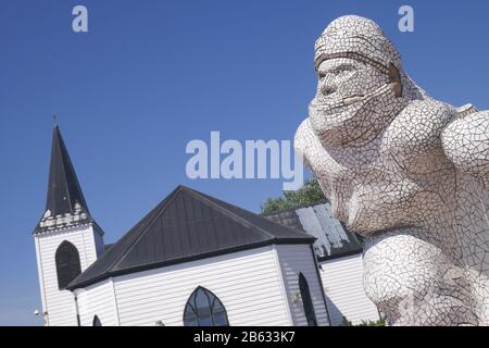 Die Scott-antarktische Gedenkstatue mit der entsektierten norwegischen Kirche, heute ein Kulturzentrum, hinter Cardiff Bay, Cardiff, Wales, Großbritannien Stockfoto