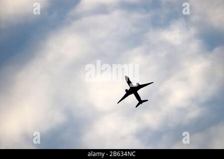 Flugzeug im blauen Himmel auf dem Hintergrund weißer Wolken fliegen. Silhouette eines kommerziellen Flugzeugs während des Climb-, Reise- und Turbulenzkonzepts Stockfoto