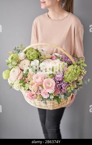 Blumen Lieferung. Blumenarrangement im großen Korbkorb. Wunderschöner Blumenstrauß aus gemischten Blumen in der Hand der Frau. Blumengeschäft Konzept . Schön frisch Stockfoto