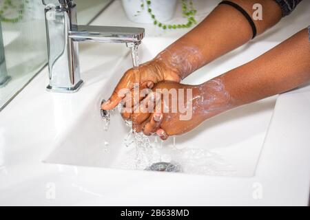 Schwarze Afrikanische Australierin waschen Hände mit Seife im Waschbecken Stockfoto