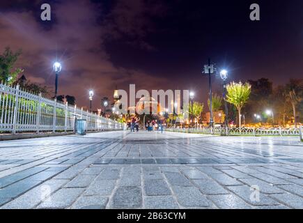 Ein Paar nimmt spät in der Nacht auf dem Sultanahmet-Platz eine selfie mit der hinter ihnen beleuchteten Hagia Sophia. Stockfoto