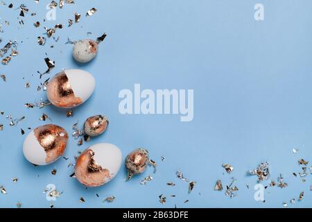 Süßer hellblauer Hintergrund mit vergoldeten Eiern und goldenem Konfetti. Stockfoto