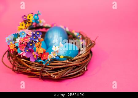 Drei blaue Ostereier im Gelege von blühenden Zweigen auf pinkfarbenem Grund. Frühlings-frommen Urlaubskonzept. Kopierbereich Stockfoto
