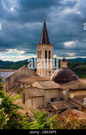 Die wunderbare Kuppel und der Kirchturm der Kathedrale von Spoleto, ein Wahrzeichen der Stadt, das im 13. Jahrhundert fertiggestellt wurde und über stürmischen Wolken stand Stockfoto