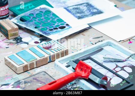 Druckwerkzeuge und Materialien auf unordentliche Tischplatte im Studio Stockfoto