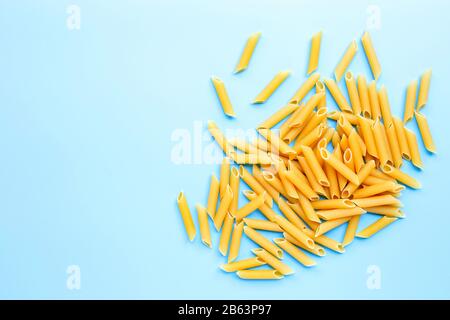 Unbehackte Penne Pasta isoliert auf blauem Hintergrund. Kopierbereich Stockfoto