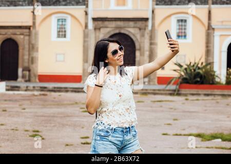 Porträt einer mexikanischen jungen Frau, die im Urlaub in Mexiko-Stadt ein Smartphone hält Stockfoto