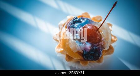 Kuchenkorb mit Früchten und roter Kirsche auf dem dunkelblauen Tisch Stockfoto