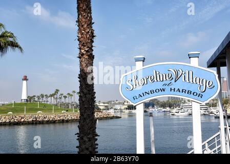 Long BEACH, KALIFORNIEN - 06. März 2020: Schild "Shoreline Village" am Rainbow Harbour mit Leuchtturm in der Ferne. Stockfoto