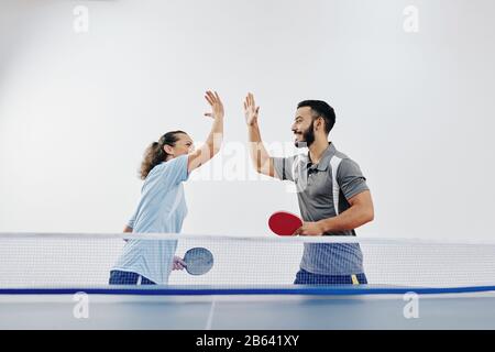 Glückliches Team von Tennisspielern, die sich nach dem Sieg im Wettkampf fünf hoch gaben Stockfoto