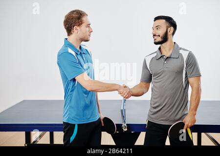 Professionelle Tischtennisspieler schütteln die Hände, bevor sie beim Wettkampf spielen Stockfoto