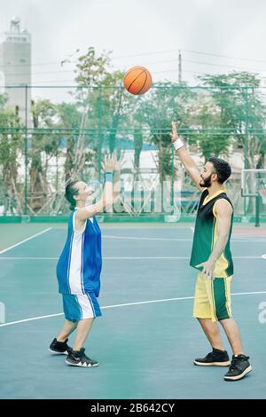 Verbinden Sie sich mit Sportkleidung, und spielen Sie gemeinsam auf dem Außenplatz Basketball Stockfoto