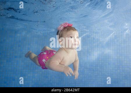 Kleines Baby lernt, unter Wasser in einem Schwimmbad, Ukraine zu schwimmen Stockfoto