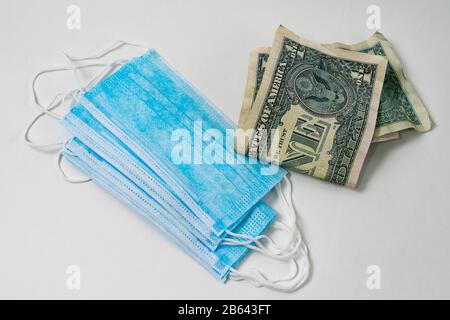 Antivirale chirurgische Masken und Geld. Hohe Gewinne aus der steigenden Nachfrage nach Schutz vor Virusinfektionen. Stockfoto