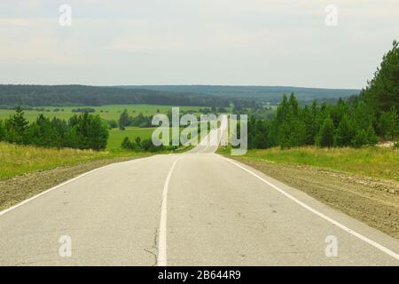 Die Straße geht hinunter und geht in die Ferne Stockfoto