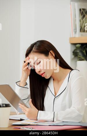 Betonte junge Managerin, die sich nach der Arbeit am Projekt den ganzen Tag über Kopfschmerzen bereitet Stockfoto