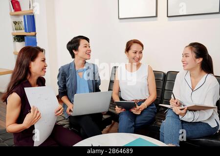Team erfolgreicher Geschäftsfrauen, die über die Unternehmensentwicklung sprechen und wichtige Gedanken beim Treffen im Büro aufschreiben Stockfoto