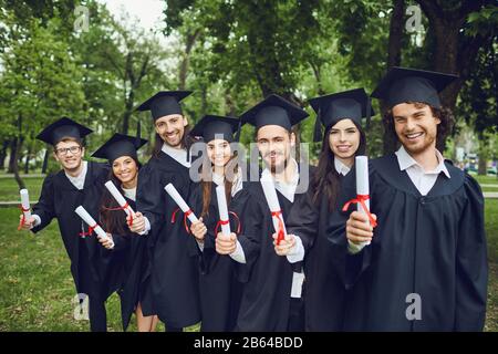 Eine Gruppe von Absolventen mit Rollen in den Händen lächelt Stockfoto