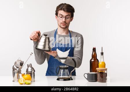 Barista, Café-Mitarbeiter und Barkeeper Konzept. Portrait eines sorgfältigen jungen, ernsthaft aussehenden jungen Mannes in der Schürze, der während der Zeit Wasser aus dem Wasserkocher in chemex gießt Stockfoto