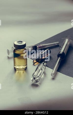 Medikamentengruppe chaotisch auf hellgrauem Hintergrund. Spritzen, Flaschen und Ampullen aus nächster Nähe. Routinemäßige Impfung des Patienten. Augenhöhe Shoo Stockfoto
