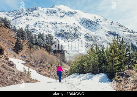 Junge Frau Wanderer, die am frühen Frühling in den Kaukasusbergen auf dem Bergpfad wandern Stockfoto