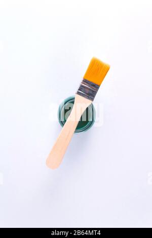 Draufsicht auf kleine Bürsten mit Holzgriff und grünem Aquarellanstrich in neu geöffneter Dose auf hellem Hintergrund. Stockfoto