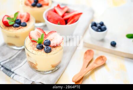 Hausgemachte italienische Dessert Tiramisu mit Erdbeeren, Minze und Kakao in Gläsern, Ansicht von oben Stockfoto