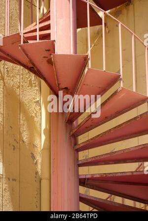 Wendeltreppen, die von Stockwerk zu Stockwerk außerhalb eines gelb gestrichenen Gebäudes gehen. Stockfoto