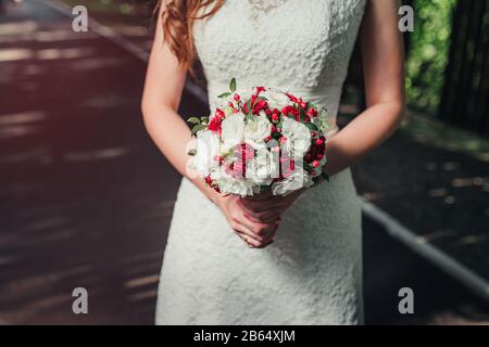 Brautpaar mit wunderschönem Blumenstrauß für die Hochzeit in Rot Stockfoto