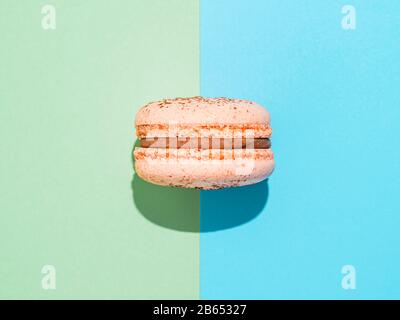 Rosa Makaron auf zwei Farben Papierhintergrund Perfekte französische Makronen oder Makronen auf blauem und grünem Hintergrund. Draufsicht oder flache Lage. Hartes Licht Stockfoto