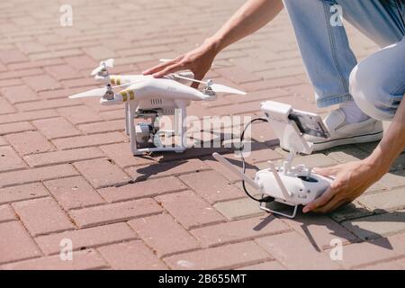 Bediener, der die Fernbedienung und den Quadrocopter hält. Unbemannter Luftkopher beginnt in Wald. Aeromodeling, Hobby, Freizeitkonzept Stockfoto