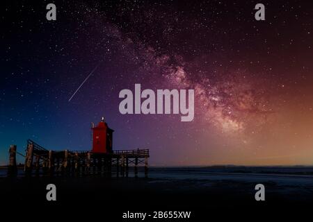 Der milchige Weg in den Himmel über einem alten Holz-Leuchtturm auf dem Meer Stockfoto