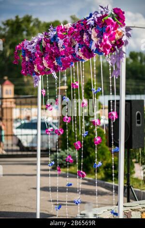 Schöne weiße Hochzeit Bogen dekoriert mit rosa und rote Blüten im freien Stockfoto