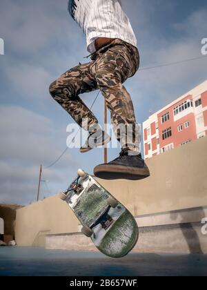 Nahaufnahme der Beine eines Skateboarders, der beim Trick vom Brett fällt. Stockfoto