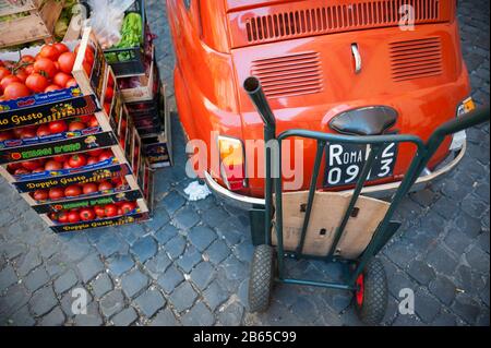 ROM - 12. MAI 2012: Stapel frischen italienischen Gemüses stehen bereit zum Auspacken neben einem kleinen roten Oldtimer des Fiats 500, der auf der Straße geparkt ist. Stockfoto