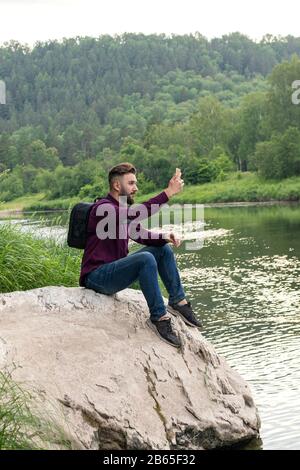 Junger Mann mit Handy, bärtiger Flusspferde, der selfie macht. Urlaub, Tourismus, Internet, Technologiekonzept. Stockfoto