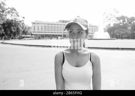 Junge schöne asiatische Touristenfrau gegen Blick auf das historische Gebäude Stockfoto