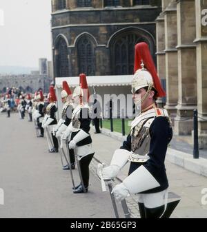 1960er Jahre, historische Soldaten des Household Cavalry Mounted Regiment, die Blues in ihren dunkelblauen Tuniken, silberne Kürasse und Helme mit roten Federn, stehend auf Zeremonie vor Windsor Castle, während des Order of the Garter, dem ältesten britischen Orden der Chivalry, Berkshire England, Großbritannien. Die Blues fusionierten 1969 mit einem anderen Regiment, den Royal Dragoons. Stockfoto