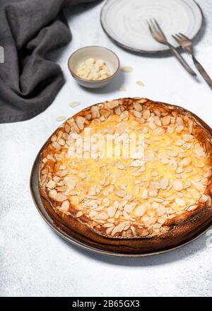 Gesunder glutenfreier Käsekuchen mit Vanillepudding und Mandelflocken auf rustikalem Hintergrund. Hausgemachtes süßes Speisekonzept. Selektiver Fokus. Stockfoto