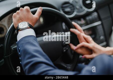 Nahaufnahme des liebenden Paares, das mit dem Auto unterwegs ist und die Hände hält. Konzentrieren Sie sich im Innenraum des Luxuswagens auf die Hände des Menschen Stockfoto