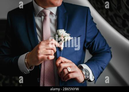 Hochzeitsdetails - eleganter, in Modetracht gekleideter Bräutigam mit luxuriöser Boutonniere wartet auf die Frau Stockfoto