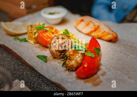 Gegrillte Salmonsteaks mit Gebackenem Gemüse, Karotten, Zwiebelpilze und Tomaten Stockfoto