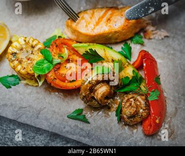 Gegrillte Salmonsteaks mit Gebackenem Gemüse, Karotten, Zwiebelpilze und Tomaten Stockfoto