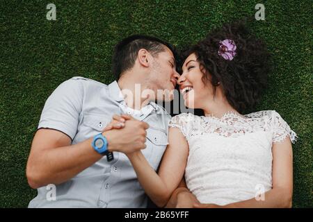 Junges süßes gemischtes Rennpaar Auf Grass Liegend. Engagement Außenaufnahmen Stockfoto