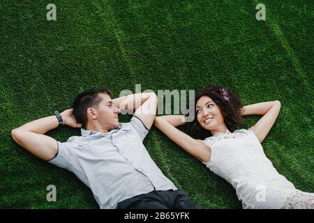 Junges süßes gemischtes Rennpaar Auf Grass Liegend. Engagement Außenaufnahmen Stockfoto