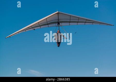 Drachenfliegerpilot und seinen Flügel hängen. Hanggleiter-Flügel gegen strahlend blauen Himmel. Stockfoto