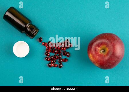 Das Konzept, Pillen gegen Äpfel zu oppontieren. Auf blauem Hintergrund verteilen Stockfoto